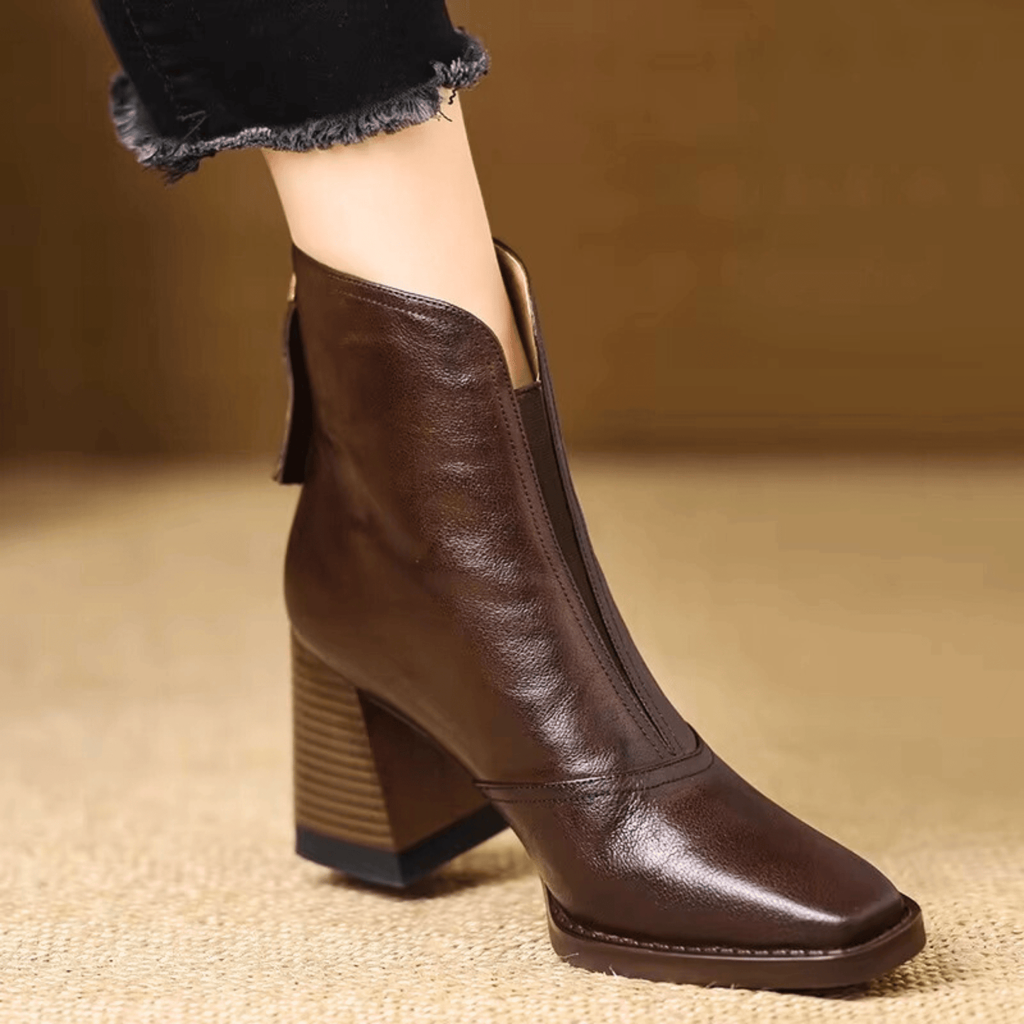 Brown leather boot on a textured surface with a blurred background